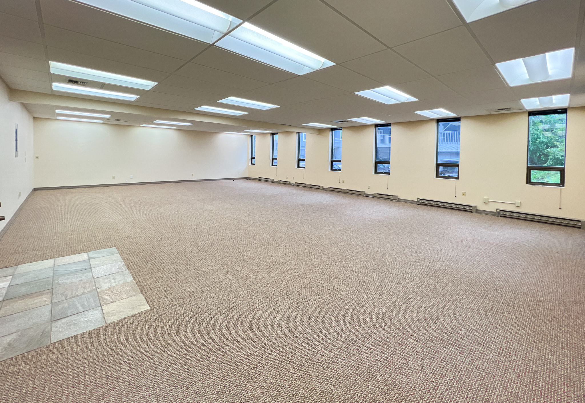 Interior of RSD Properties' Suite 102 in the 750 W 2nd Avenue office commercial office building in Anchorage, Alaska. Several windows on the right, tan carpeting and a drop ceiling