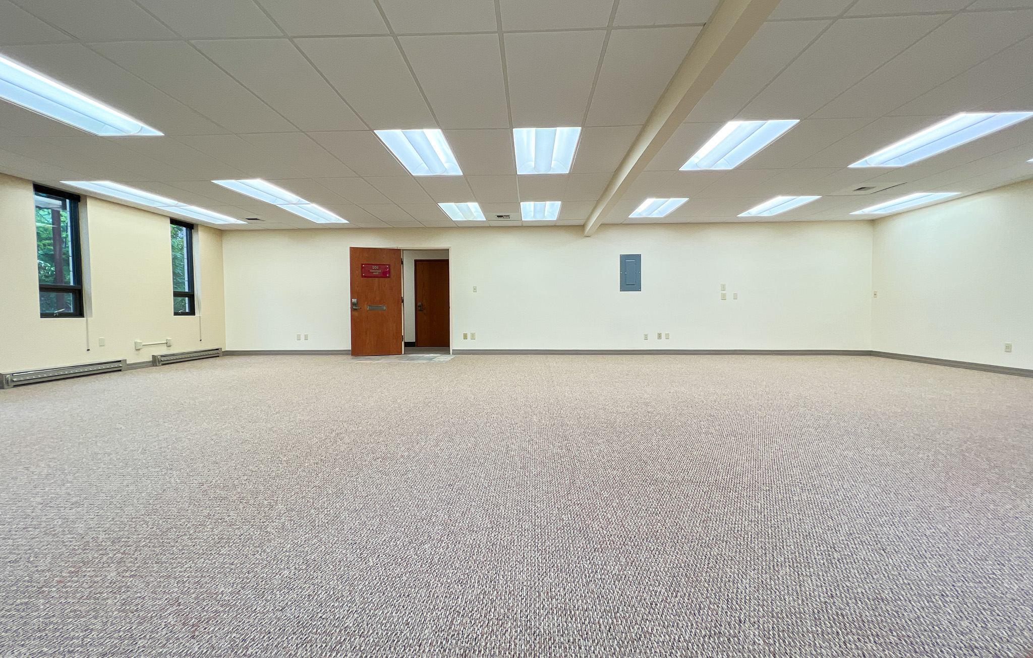 Interior of RSD Properties' Suite 102 in the 750 W 2nd Avenue office commercial office building in Anchorage, Alaska. Two windows on the left, tan carpeting and a drop ceiling with brown exit door center left