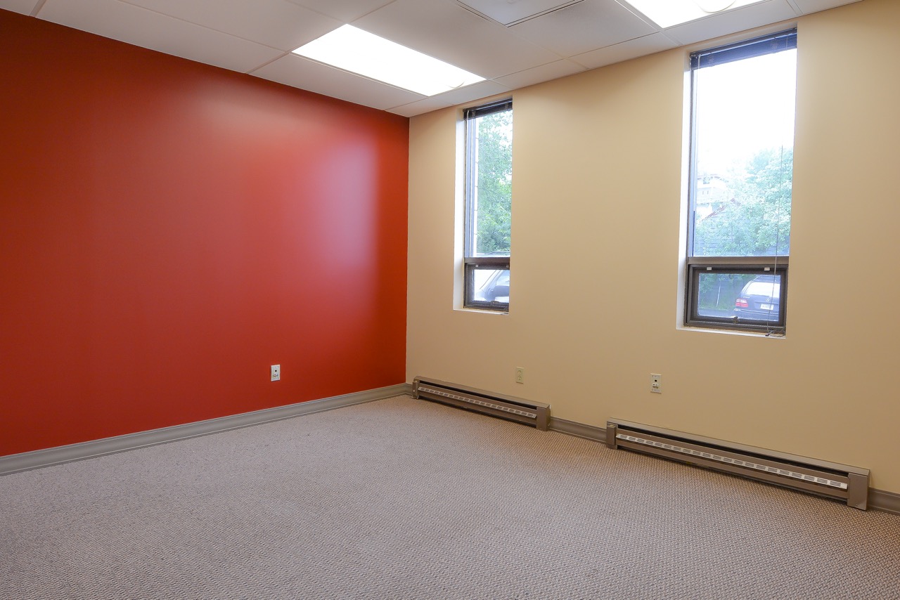 Interior of RSD Properties' Suite 101 in the 750 W 2nd Avenue commercial office building, in Anchorage, Alaska. Red wall on the left, tan wall and windows on the right, tan carpet.