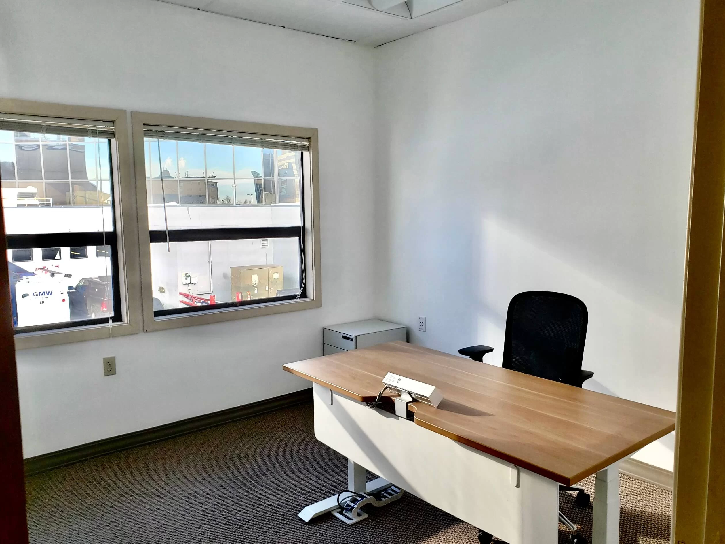 A coworking office at RSD Properties' Cowork by RSD 921 Annex with windows on the left showing a beautiful Anchorage, Alaska day, and a small desk with chair and filing cabinet on the right